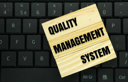laptop keyboards and wooden boards with the words quality management system