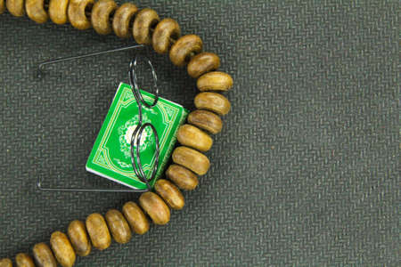 rosaries, spectacles and the form of the Quran with a gekap background. Islamic concept.