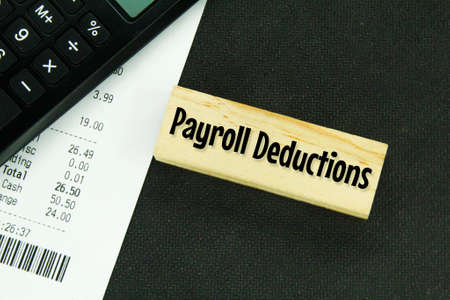 calculators, receipts and wooden boards with the word payroll deductions