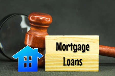 wooden hammers, paper houses and wooden boards with the word mortgage loans