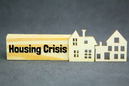 wooden house models and wooden boards with the word housing crisis