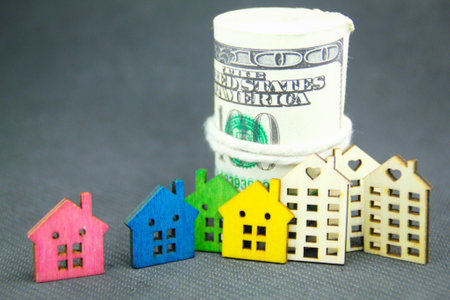 the shape of a colored wooden house and a roll of money with the concept of buying a new houseの写真素材