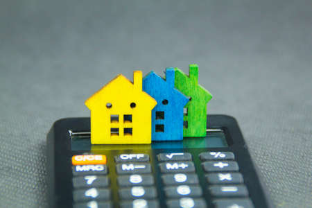The house is placed on a calculator. Plan coin savings to buy concept homes for real estate,...