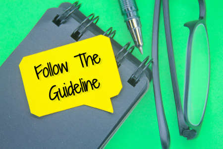 glasses, pen san notebook with the words Follow The Guidelinesの写真素材