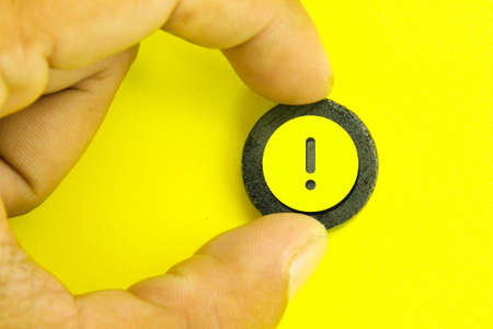 hand holding a colored wooden circle with an exclamation mark iconの写真素材