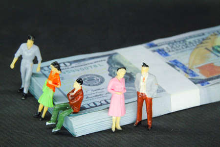 miniature men and women with money backgrounds and calculators. The concept of a business partner