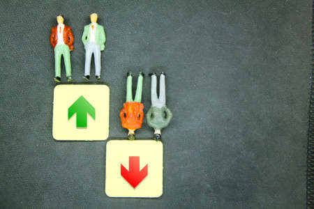 miniature people and wooden hexagons with business graph icons going up and down. Business...