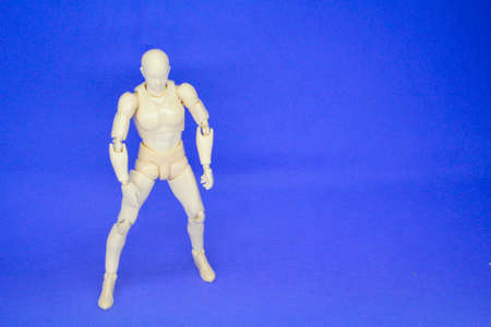 Jointed male wooden mannequins are isolated on a blue background