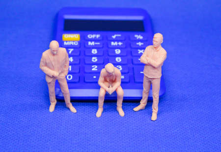 miniature people or small people and calculator. the concept of a business partner. Selective focus....