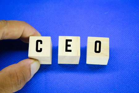 hand holding CEO alphabet letter on blue background. chief executive officerの写真素材