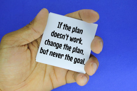 hand holding paper with the words If the plan doesn't work, change the plan, but never the goalの写真素材