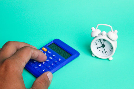 hand holding a calculator and next to a bell clock. accountant concept Or mathematic
