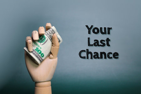 wooden hand holding paper money with the words Your last chance