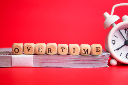 bell clock and small wooden cube with the word overtime. overtime conceptの写真素材