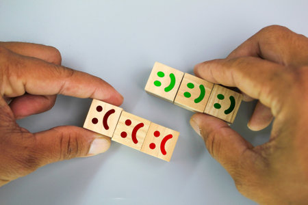 hand holding a wooden cube with an angry and happy facial expression. smiling and sad emoticon....