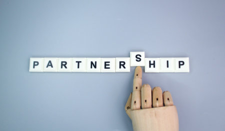 wooden hand and alphabet letters with the word partnership. concept of partner or partnership