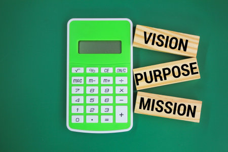calculator and a wooden board with the three words Vision Purpose Mission. Business and Vision Purpose Mission concept.の写真素材