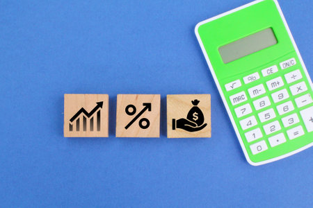 calculator and wooden squares with income icons, rising graphs and percentages. profit concept. the...