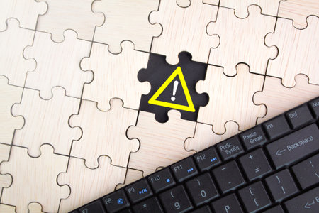 wooden puzzle with caution icon. warning or alert software, virus or threat online, scam, user typing on computer keyboard, access caution icon, malicious cyber attackの写真素材