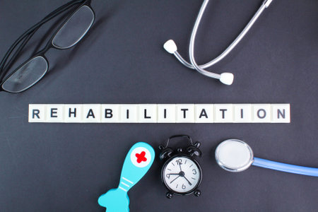 stethoscope, alarm clock, glasses and the word alphabet rehabilitation. concept of recoveryの写真素材