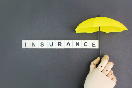 wooden hand holding an umbrella with the word insurance alphabet letters. the concept of insurance or insurance coverageの写真素材