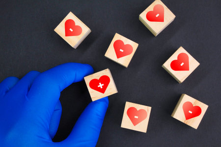 hand holding a wooden cube with healthy and unhealthy icons. health concept. positive and negative heartsの写真素材