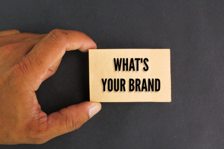 A hand holding a card that says what's your brand. the concept of creating your own brandの写真素材