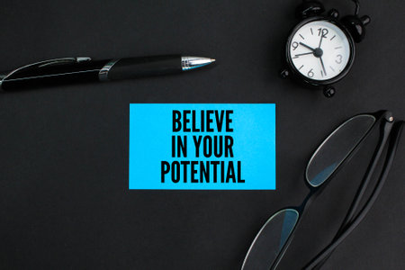 pen, glasses and an alarm clock with the words Believe In Your Potential. the concept of self-beliefの写真素材