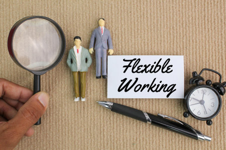 miniature people, bell clock, pen and magnifying glass with the word Flexible workingの写真素材