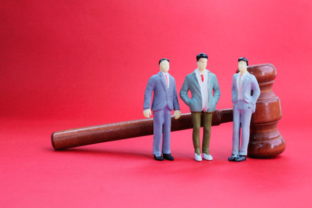three miniature people with a judge's gavel behind. employment law conceptの写真素材