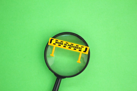 magnifying lenses and signage with the word work in progress. the concept of maintenance or under maintenanceの写真素材