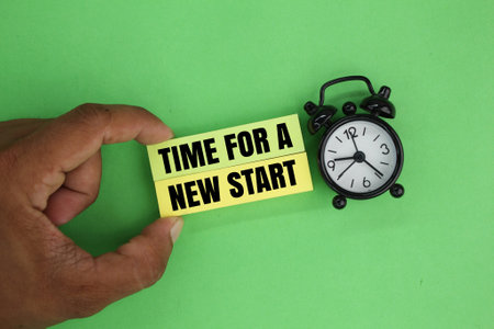bell clock and hand holding colored paper with the words Time for a new start. reset conceptの写真素材