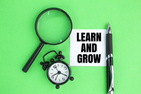 a pen, an alarm clock and a magnifying glass with the words Learn and grow. the concept of learning and growingの写真素材