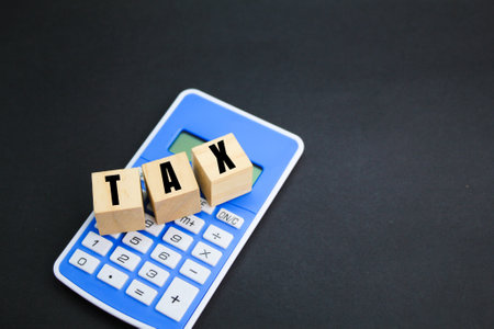 a calculator and a wooden cube with the word TAX. tax business conceptの写真素材