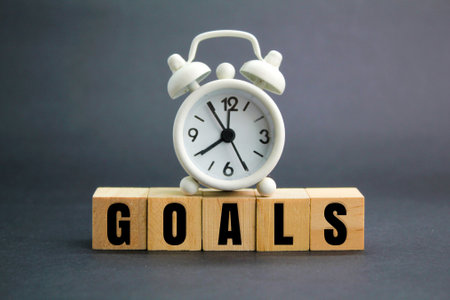 bell clock and wooden cube with the word goals. concept of goal or purpose