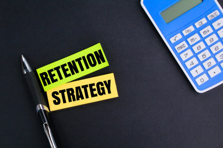 calculator, pen and colored paper with the word retention strategy. strategy concept for retentionの写真素材