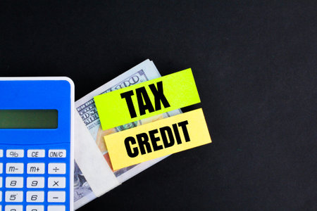 calculator, paper money and colored paper with the word Tax credit. tax credit conceptの写真素材