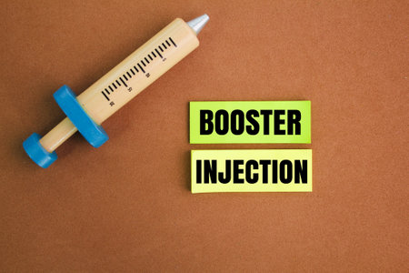 needle shape and colored paper with the word booster injection. health and medical concepts. the...