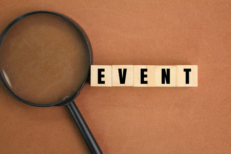 magnifying glass and wooden cube with the word event. the concept of an event or something that will...