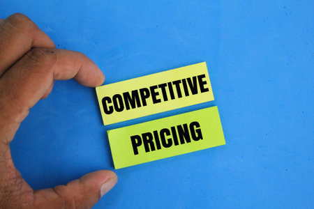 hand holding colored paper with the word COMPETITIVE PRICING. the concept of competitive pricing....