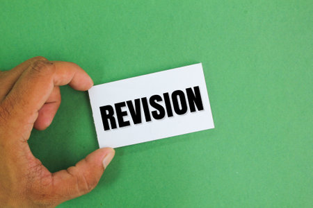 hand holding a white paper with the word Revision. the concept of review or inspection