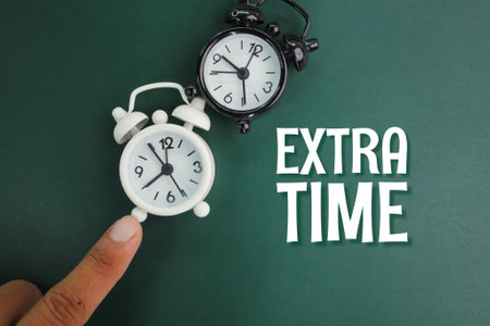 black and white alarm clock with the word extra time. match time extension. a further period of play added on to a gameの写真素材