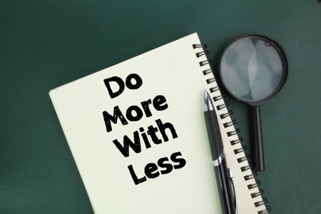 magnifying glass, pen and book with the words Do more with lessの写真素材