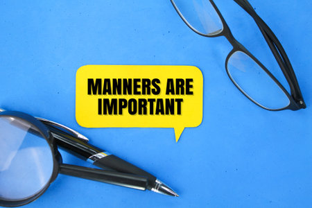magnifying glass, glasses, pen and colored paper with the words manners are important. about discipline or mannersの写真素材