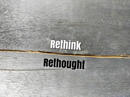 Cracked dark wood background with the words rethink or rethought. thinking conceptの写真素材