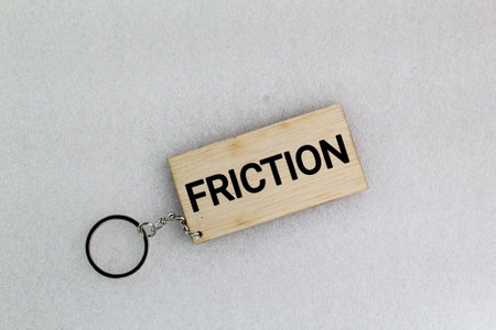 wooden tag or keychain with the word Friction. the resistance that one surfaceの写真素材