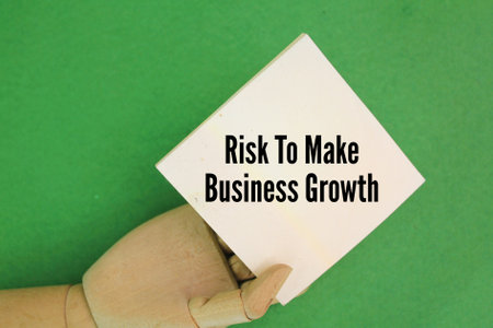 wooden hand holding paper with the word risk to make business growth