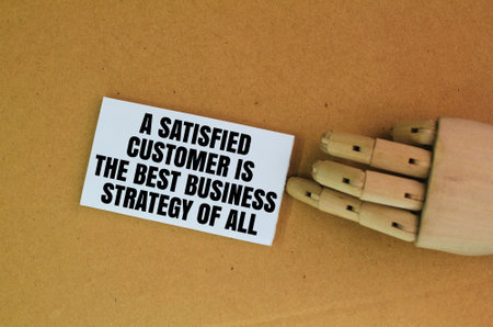 wooden hand and white paper with the words A Satisfied Customer Is The Best Business Strategy of Allの写真素材