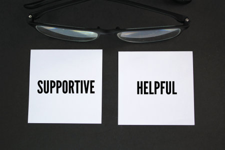 glasses and two white papers with the words supportive or helpful
