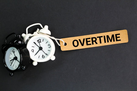 two clock bells and a paper tag with the word overtime. overtime concept